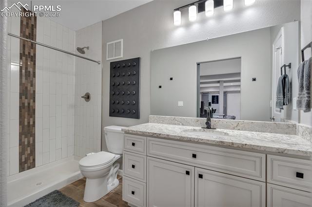 615 Cimarron Road Monument, CO 80132 - Photo 38 of 50 Bathroom featuring vanity, tiled shower, and wood finished floors