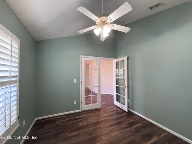 an empty room with wooden floor cabinet and windows