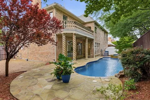 a view of a white house with a yard potted plants and large tree
