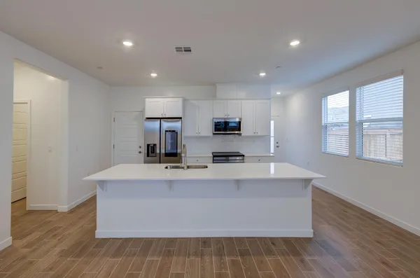 a large kitchen with stainless steel appliances a large counter top a wooden floor a fireplace and a window