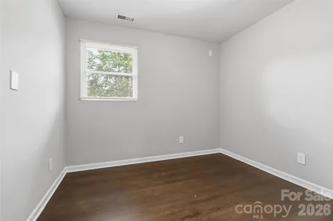 an empty room with wooden floor and window