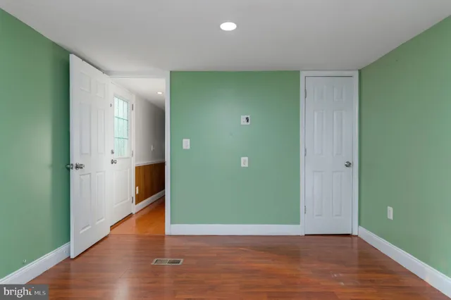 a view of an empty room with wooden floor and entrance