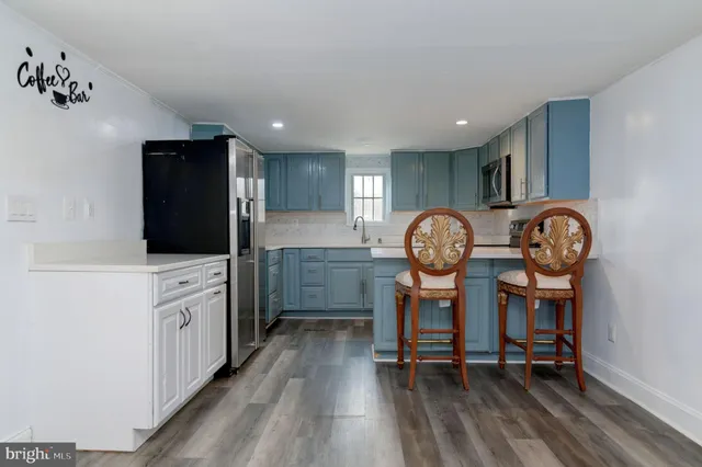 a kitchen with granite countertop a stove refrigerator a oven a dining table and chairs with wooden floor