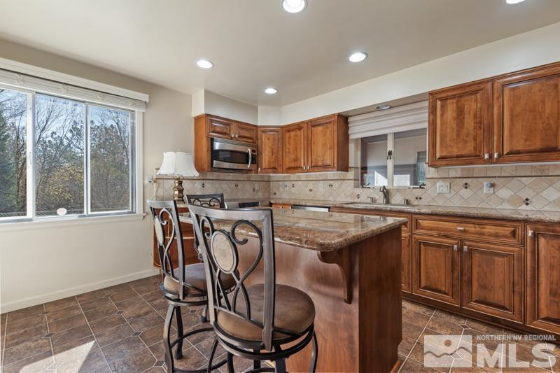 2250 Foothill Road Reno, NV 89511 - Photo 11 of 37 a kitchen with stainless steel appliances granite countertop a table chairs sink refrigerator and microwave