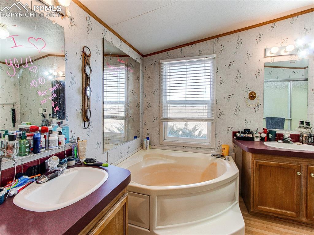 4491 Lauppe Road Yoder, CO 80864 - Photo 22 of 27 a bath tub sitting next to a bathroom sink and a mirror