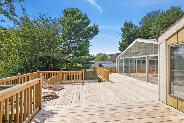 a view of roof deck with wooden floor and fence next to a yard