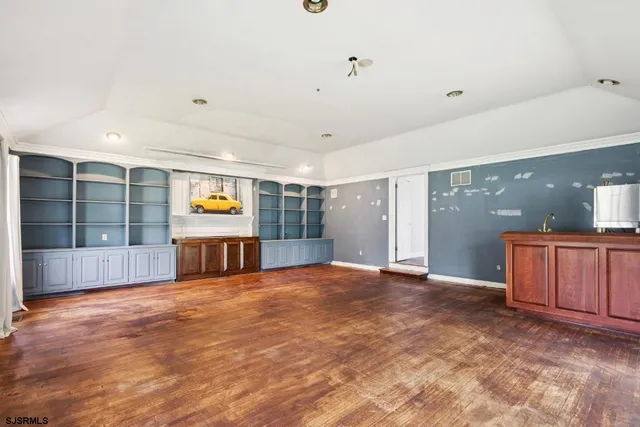 a view of an empty room with a window and a kitchen