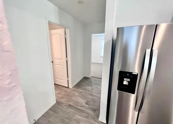 a view of a refrigerator in kitchen and an empty room