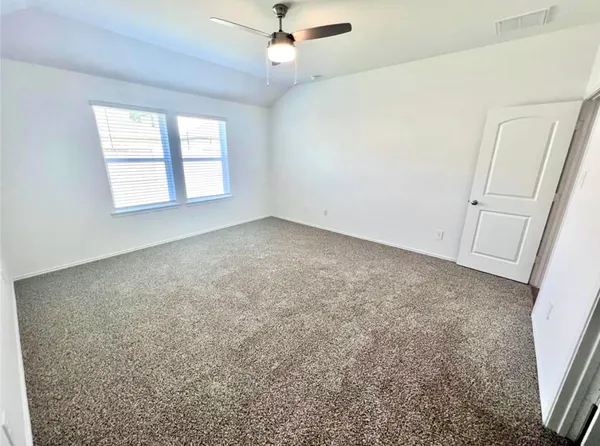 en empty room with windows and ceiling fan