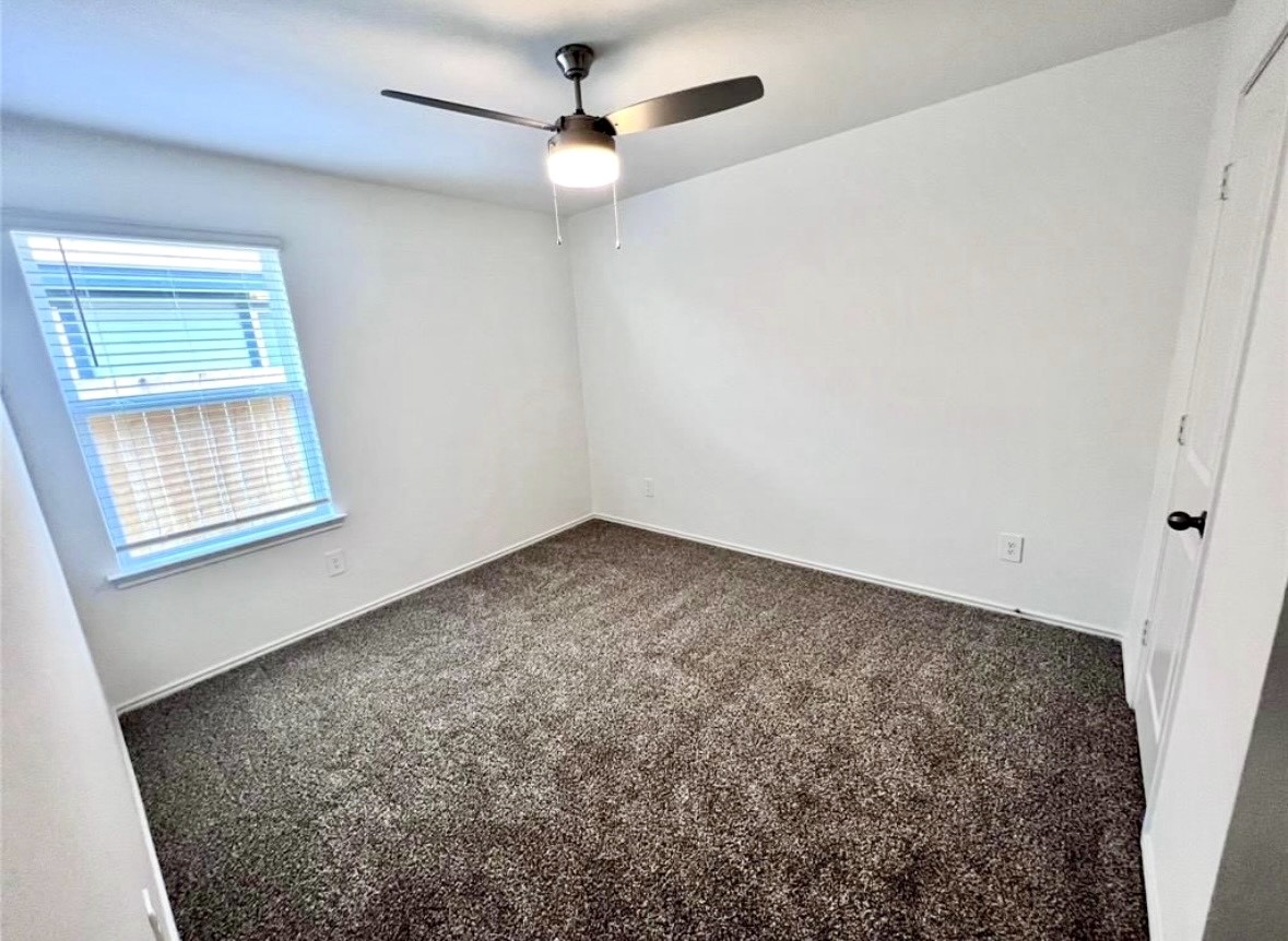 14220 Fern Meadows Drive Splendora, TX 77372 - Photo 19 of 22 an empty room with a chandelier fan and windows