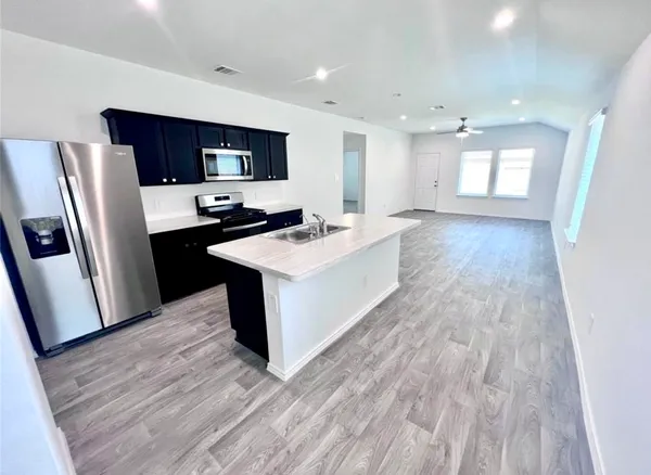a kitchen with stainless steel appliances a refrigerator sink and wooden floor