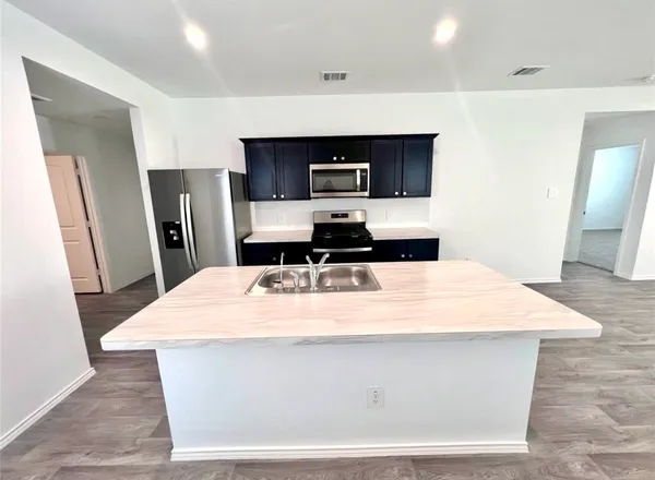 a room with stainless steel appliances kitchen island sink refrigerator and stove