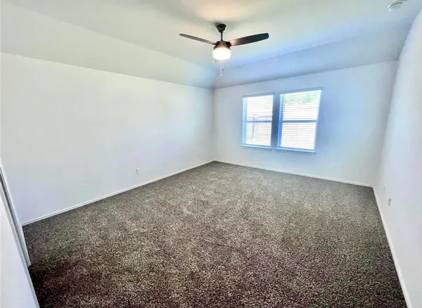 an empty room with windows and ceiling fan