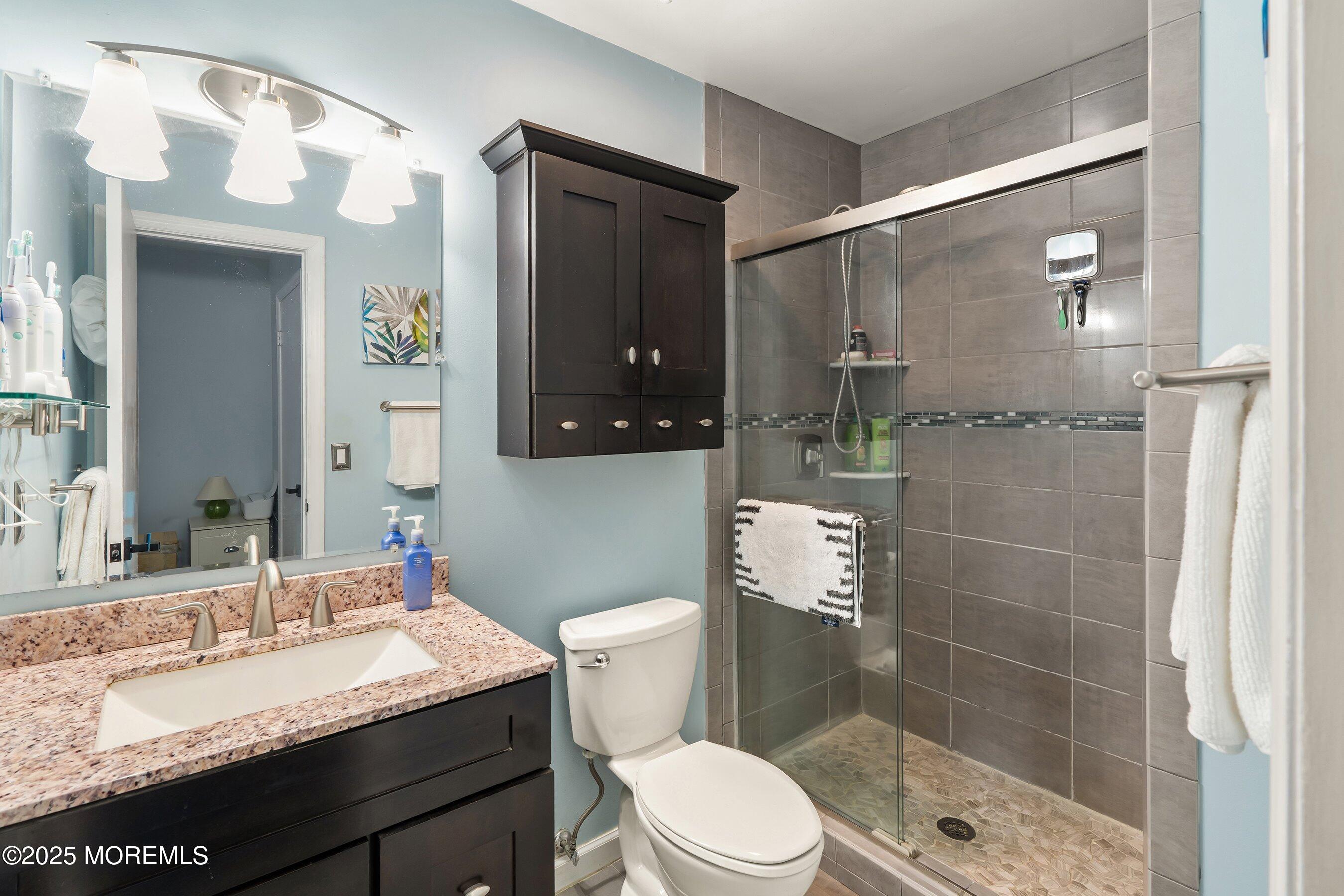 10 Cove Court Howell, NJ 07731 - Photo 20 of 40 a bathroom with a granite countertop sink toilet a mirror and shower