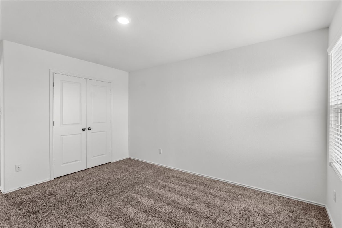448 Perfect World Loop Jarrell, TX 76537 - Photo 37 of 40 A well-lit bedroom features plush carpeting and a pair of clean white doors.
