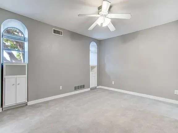 an empty room with windows and fan