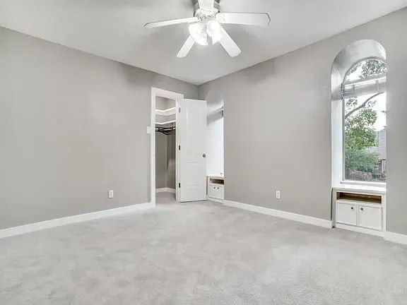 an empty room with a chandelier fan and windows