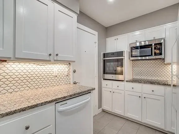 a kitchen with granite countertop white cabinets and stainless steel appliances