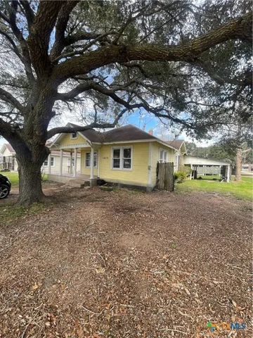 a view of a house with a tree in front of it