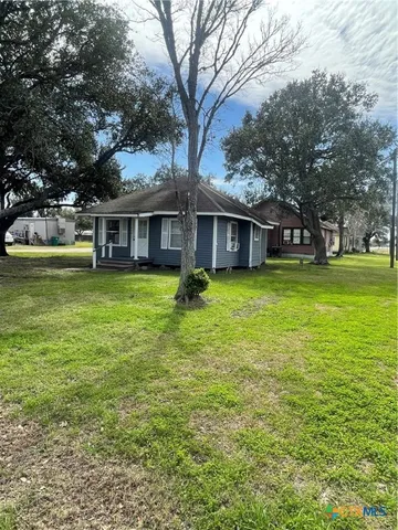 a view of a house with a big yard and large trees
