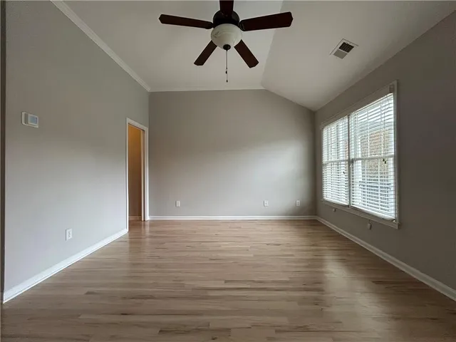 a view of an empty room with window and wooden floor