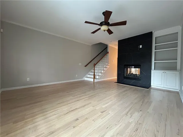 a view of an empty room with wooden floor and a ceiling fan