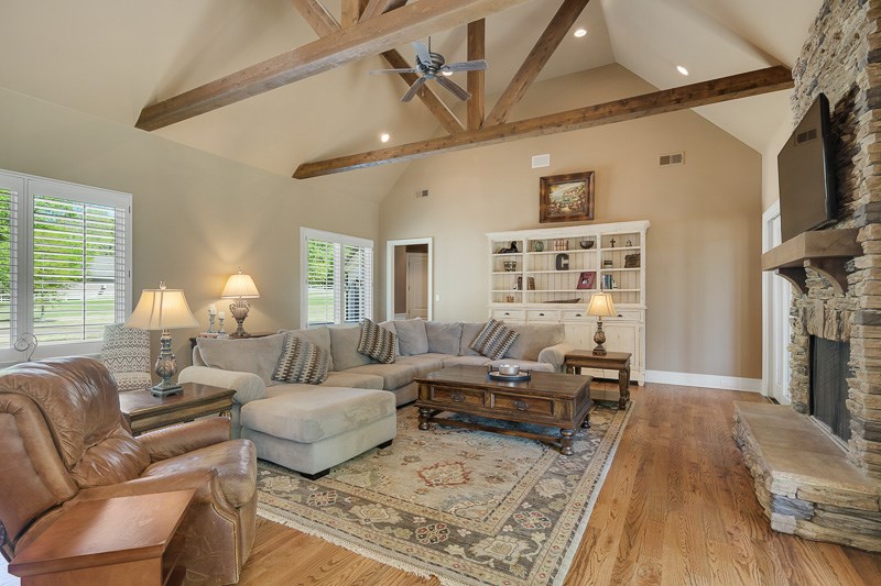 336 Pisgah Road Eads, TN 38028 - Photo 7 of 25 Expansive living space with rich hardwood floors, vaulted beamed ceiling, and stacked stone fireplace.