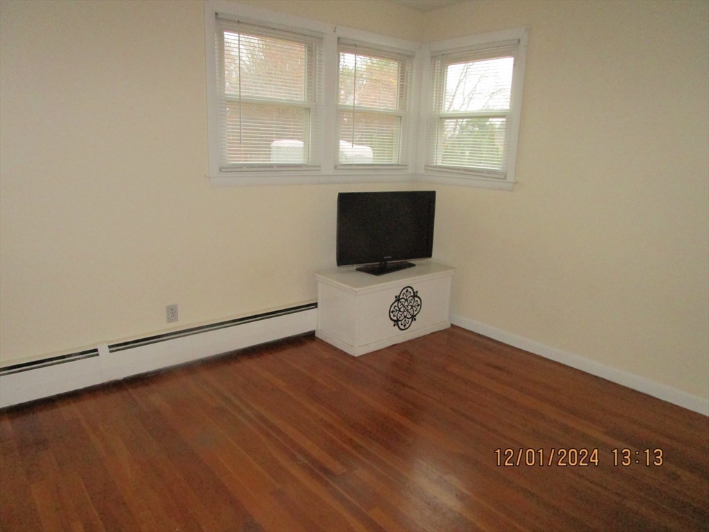 282 Central Street, Unit 1 Auburn, MA 01501 - Photo 14 of 16 a view of an empty room with wooden floor and a window