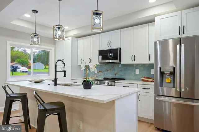 a kitchen with stainless steel appliances granite countertop a sink a stove a refrigerator a center island with a dining table and chairs