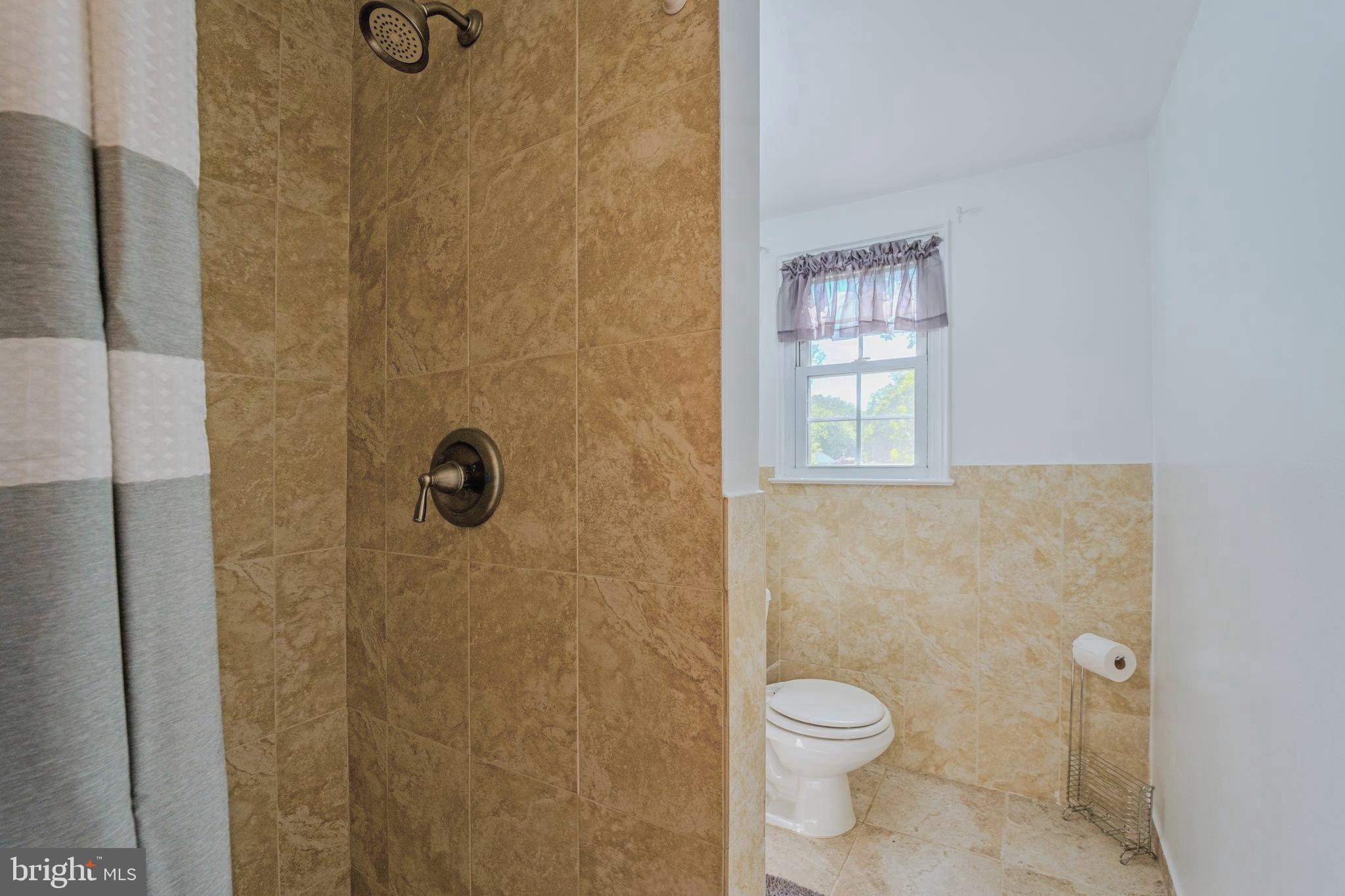 6705 Bracken Court Springfield, VA 22152 - Photo 26 of 40 a bathroom with a granite countertop toilet a sink a shower and a window