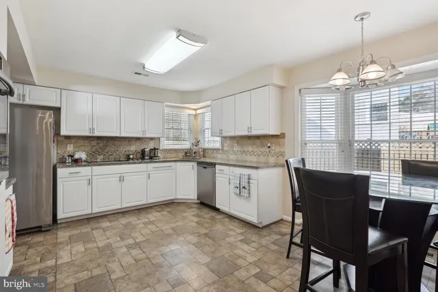 a kitchen with granite countertop cabinets stainless steel appliances dining table and a chandelier