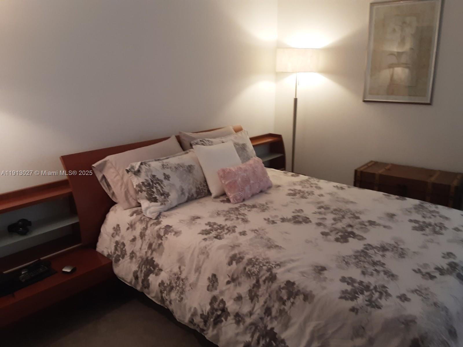 9409 Fontainebleau Boulevard, Unit 207 Miami, FL 33172 - Photo 11 of 19 a bed sitting in a bedroom next to a lamp