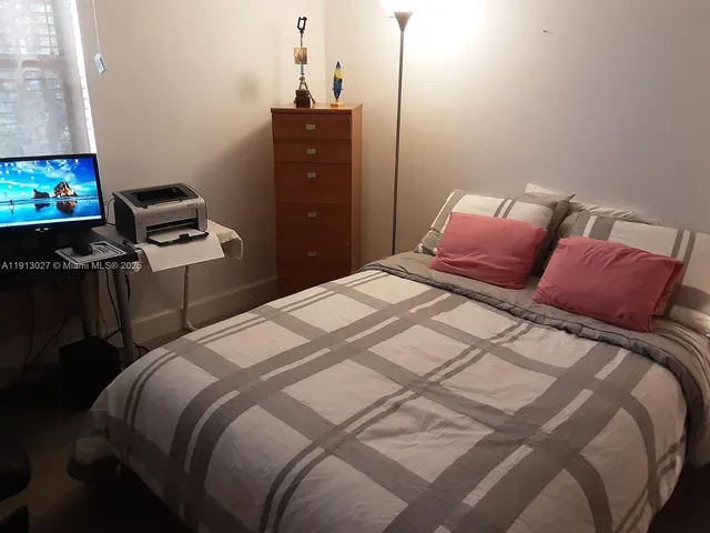 a bedroom with a bed and a flat tv screen on a dresser