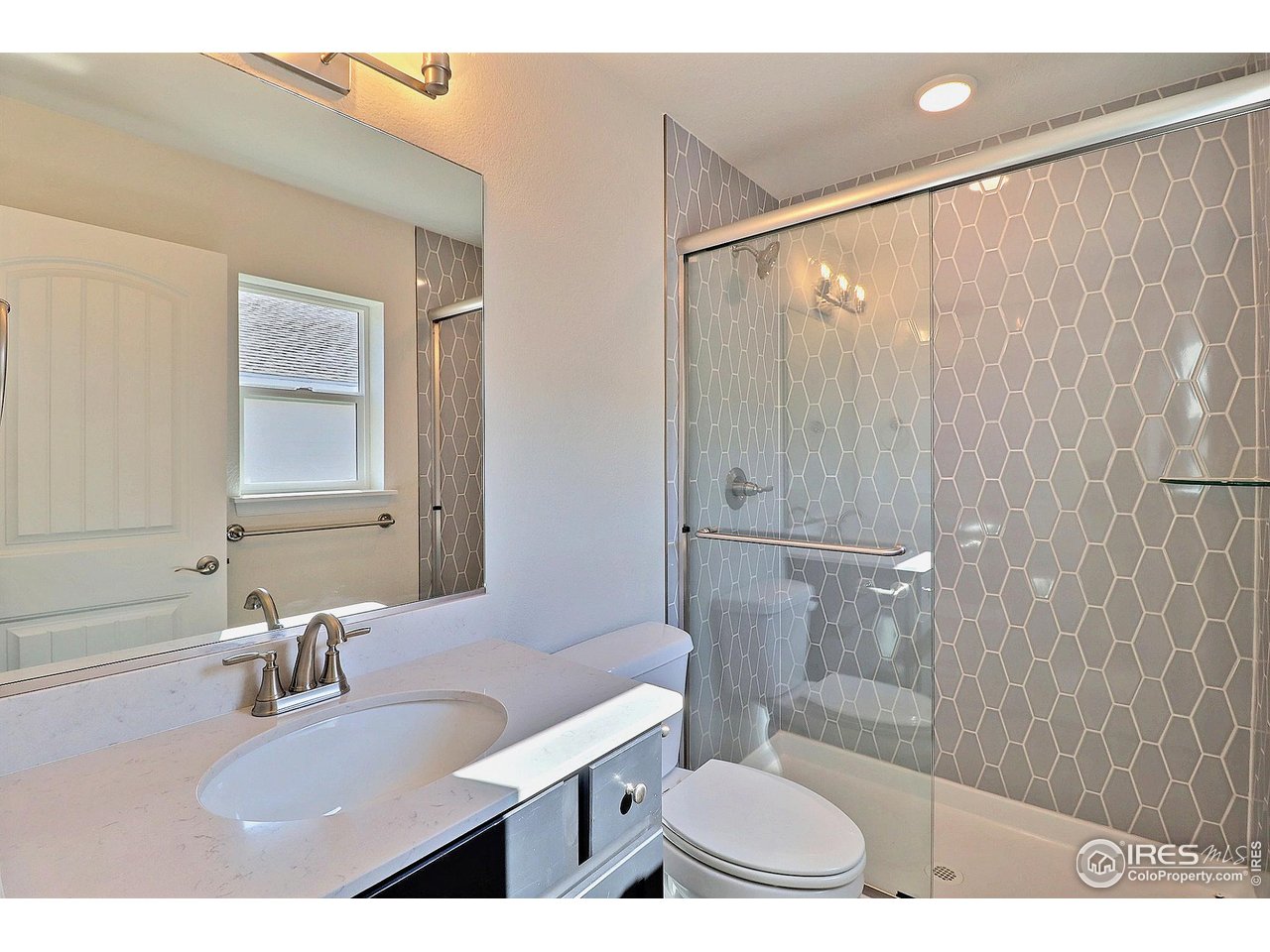 4301 Rockcress Road Evans, CO 80620 - Photo 20 of 26 a bathroom with a sink toilet a mirror and shower