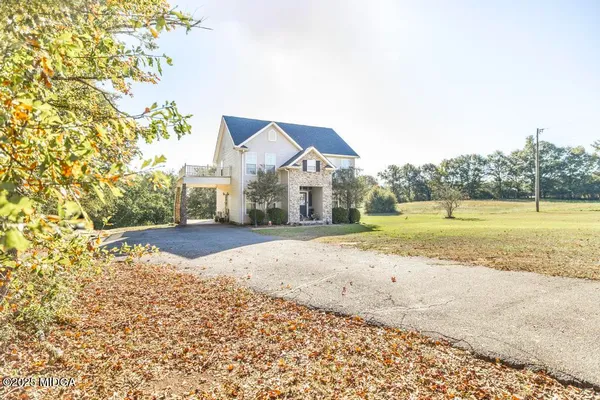 a view of a house with a yard and road