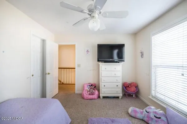 a bedroom with furniture a flat screen tv and a window