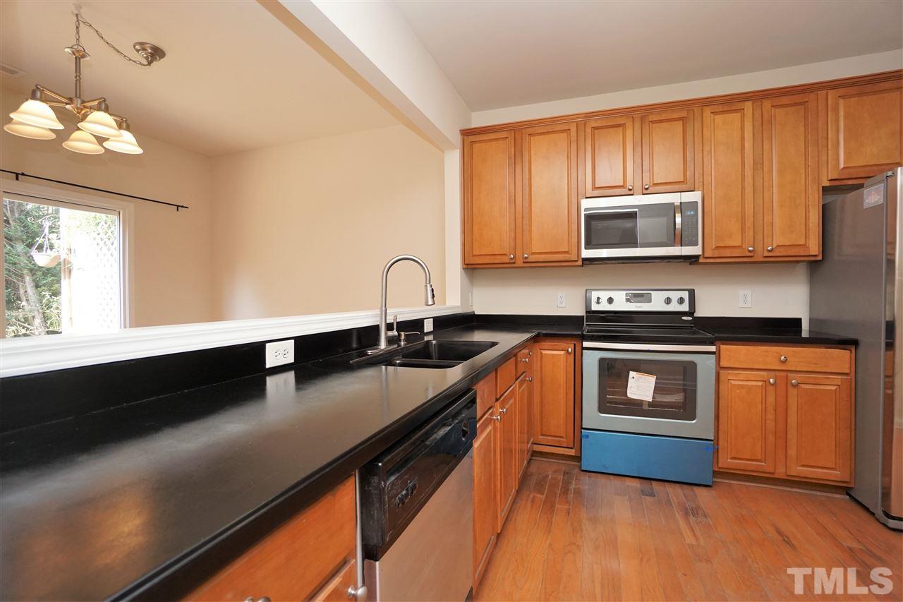 7718 Tanby Court Raleigh, NC 27613 - Photo 5 of 20 a kitchen with stainless steel appliances a sink dishwasher a stove top oven a refrigerator with wooden floors and cabinets