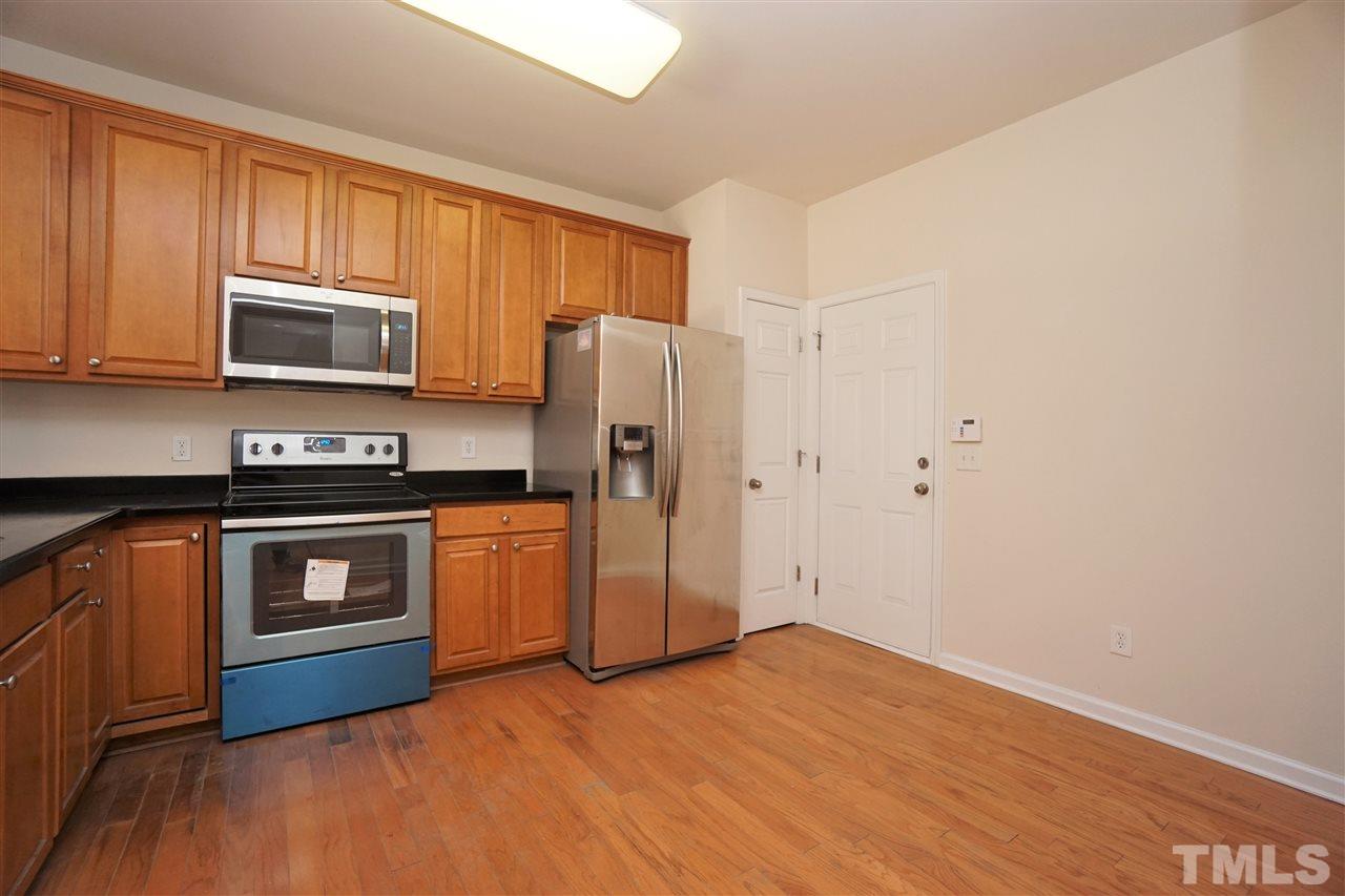 7718 Tanby Court Raleigh, NC 27613 - Photo 6 of 20 a kitchen with granite countertop wooden cabinets and stainless steel appliances