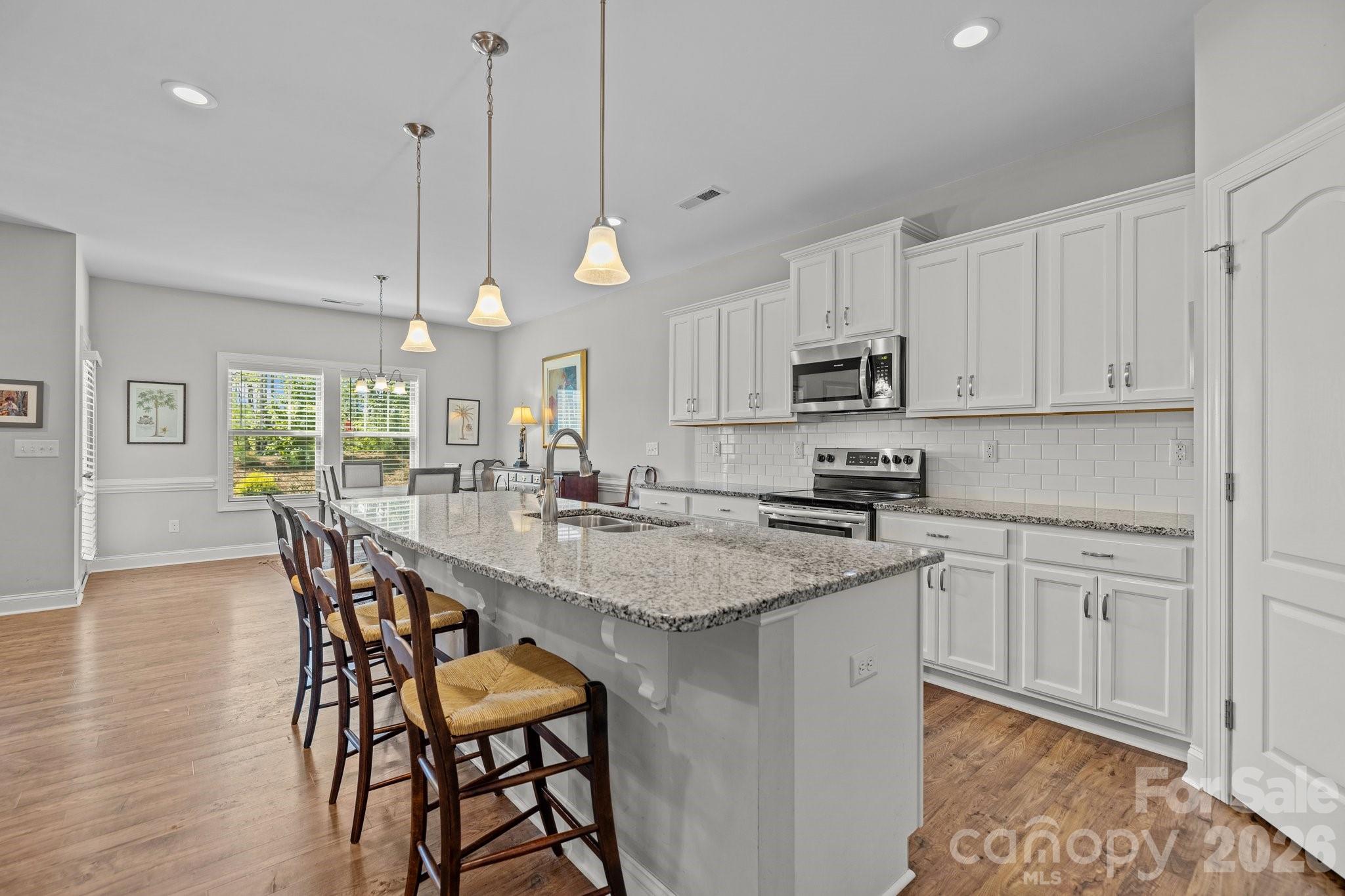 4697 Rinaldo Road York, SC 29745 - Photo 11 of 37 a kitchen with stainless steel appliances granite countertop a stove a sink a microwave a dining table and chairs with wooden floor