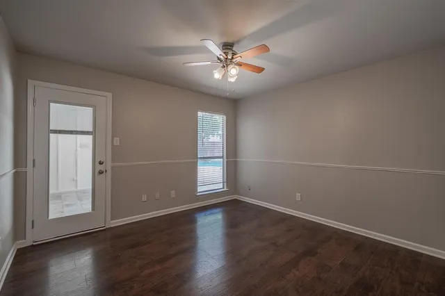 an empty room with wooden floor fan and windows