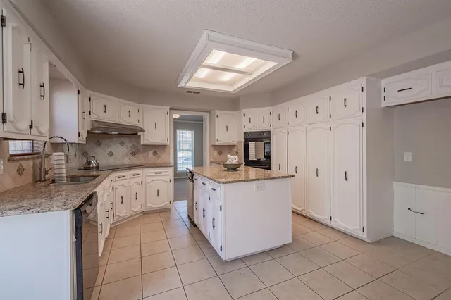 a kitchen with granite countertop a sink stove and refrigerator