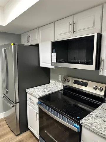 a kitchen with granite countertop a stove microwave and fridge