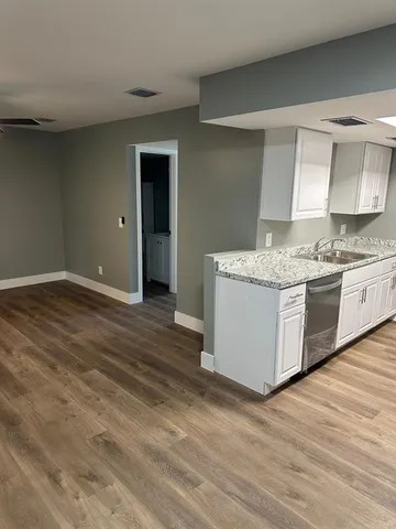 a kitchen with a sink cabinets and wooden floor