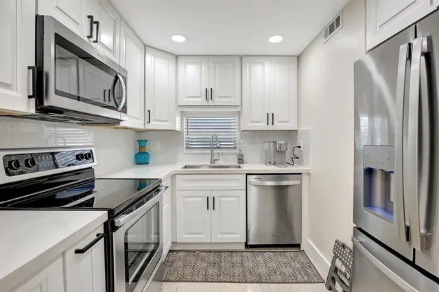 a kitchen with stainless steel appliances granite countertop a refrigerator sink and stove