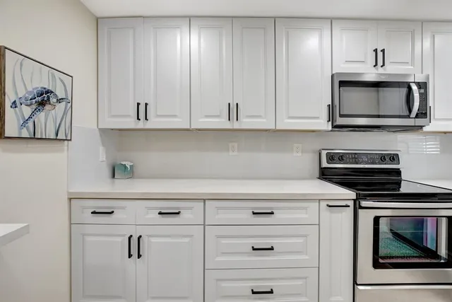 a kitchen with white cabinets and stainless steel appliances