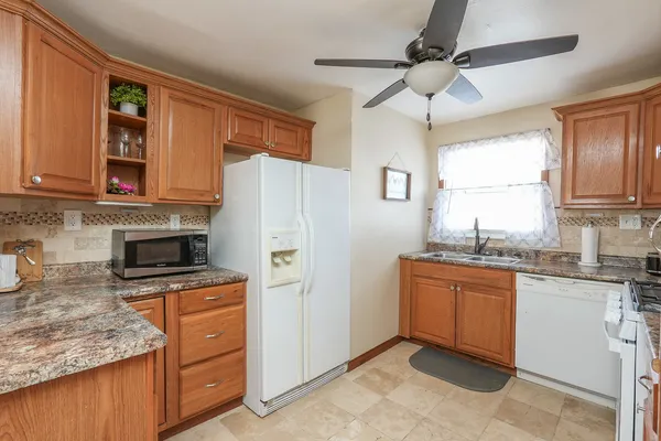 a kitchen with granite countertop a refrigerator stove top oven and sink