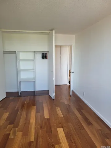 a view of an empty room with wooden floor and closet