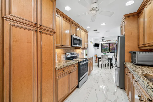 a kitchen with stainless steel appliances granite countertop a refrigerator oven a sink dishwasher and white cabinets with wooden floor