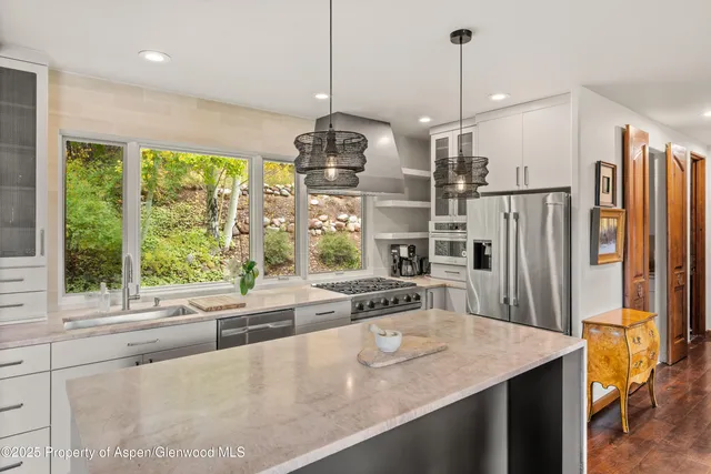 a kitchen with stainless steel appliances granite countertop a sink a stove and a refrigerator