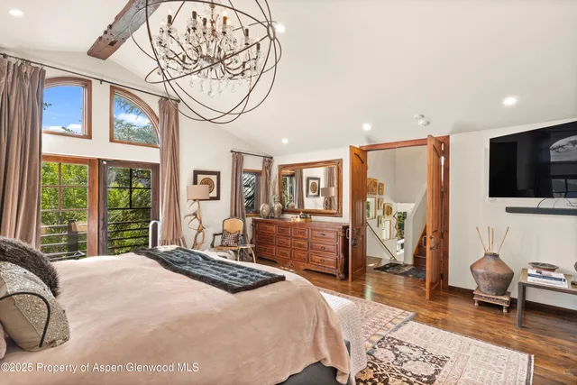 a bedroom with a large bed a flat screen tv and a large window with the garden view